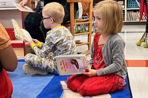 Student in a red dress reading while sitting on the floor