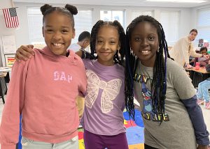 three female students post while smiling