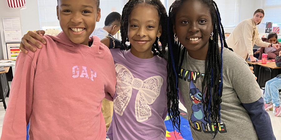 Three girls smile while posing for the camera