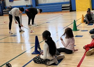 Lacrosse players demonstrating skills to young kids