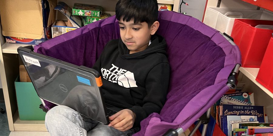 A student relaxing in a chair with a computer