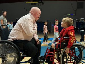 Man in a wheelchair talks to a boy in a wheelchair