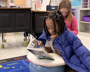 a student reads with a coat draped over her shoulders