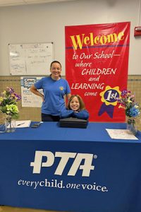 student and parent smile while standing at a table