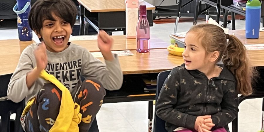 A student jumps for joy as a classmate looks on