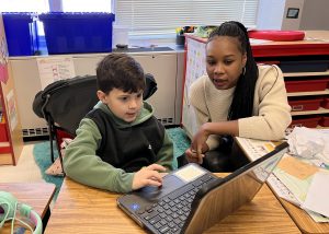 A student and teacher look at a computer