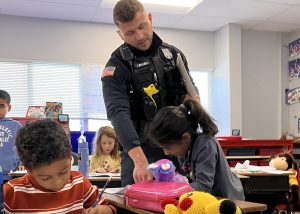 A police officer helps a student in the classroom