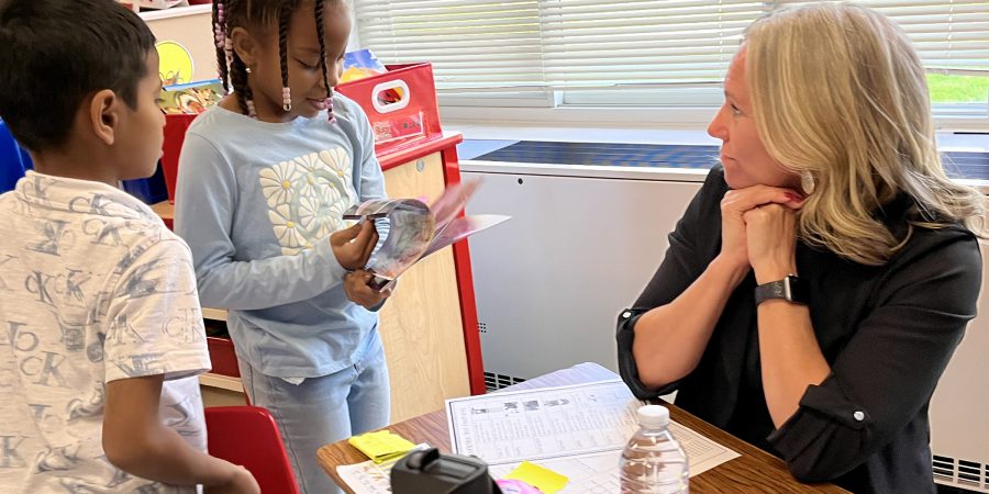 Seated principal talking to two standing second grade students