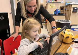 A student and principal look at a computer