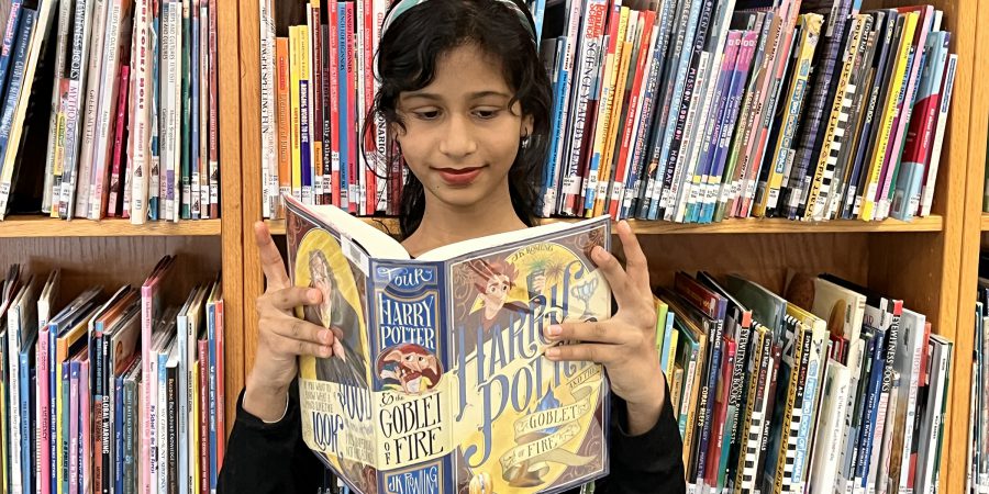 A standing student reading a Harry Potter book