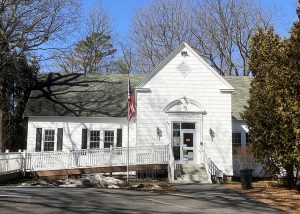 A white library building with a handicapped ramp and flag in front