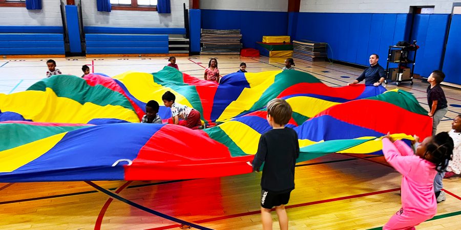 Students play with a parachute in the gym