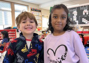 A boy and girl pose while smiling